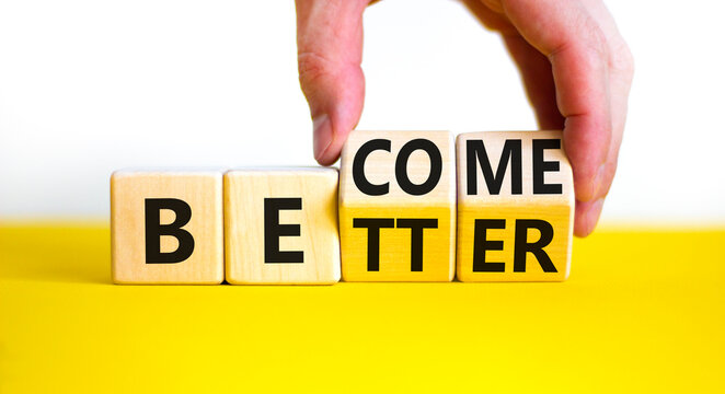 Become better symbol. Businessman turns wooden cubes and changes the concept word Better to Become. Beautiful yellow table white background. Business become better concept. Copy space.