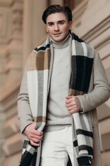  Young man wearing coat walking in the street. Young bearded guy with modern hairstyle in urban background