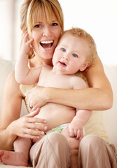 Mommys little angel. Laughing mother holding her baby boy on her lap.