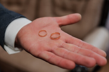 A pair of wedding gold rings in the hands of the groom. Wedding rings on a man's hand