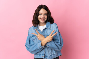 Teenager Ukrainian girl isolated on pink background smiling and showing victory sign