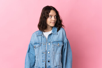 Fototapeta premium Teenager Ukrainian girl isolated on pink background having doubts while looking up