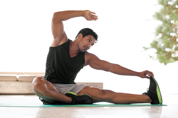 Its not a stretch to say he keeps fit. Full length shot of a handsome man stretching to touch his...
