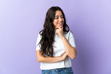 Young caucasian woman isolated on purple background looking to the side and smiling