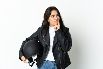 Woman holding a motorcycle helmet isolated on white background having doubts while looking up