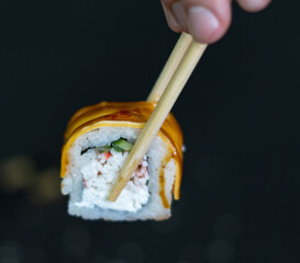 Sushi roll with cream cheese and fried salmon on dark background