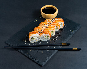 Sushi roll with cream cheese and fried salmon on dark background