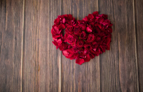 beautiful photo of a heart lined with red roses on a dark wooden floor, surprise for romantic date, valentine's day, the way to say I love you