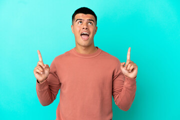 Fototapeta premium Young handsome man over isolated blue background surprised and pointing up