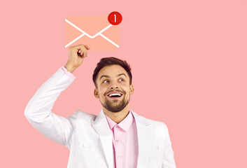 Happy handsome man holding envelope icon with red notification about new message. Cheerful businessman is notified of new mail in his inbox. Studio shot, isolated pink color text copy space background