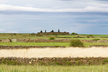 Cementerio en paisaje soleado con prados de hierba  y cercados de piedra que separan las parcelas en primavera 