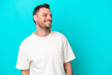 Obraz premium Young Brazilian man isolated on blue background looking to the side and smiling