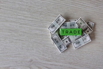 Business concept. Top view image pile of banknotes and wooden cube with text TRADE. Copy space.