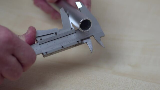 Close up view of a man measuring an aluminum pipe with an electronic calipers. Sweden.