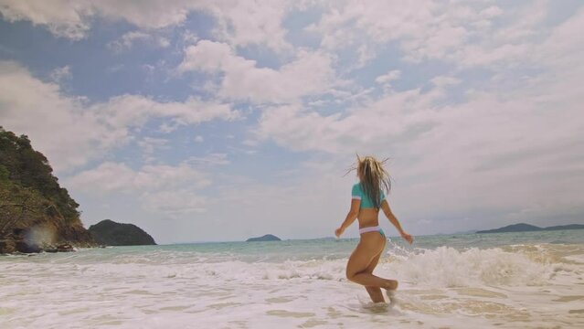 Crazy madwoman daring funny woman running on the sea. Happy slightly tipsy woman enjoying her vacation on a tropical island. Smiling girl funny posing. Concept summer holidays