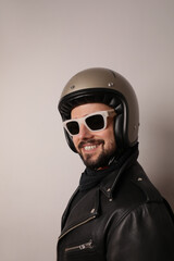 Vertical portrait of bearded happy biker man in leather jacket and retro helmet.