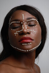 Close-up of beautiful African black woman with pearls on her face. Vertical.