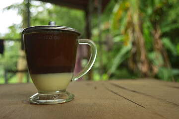 Photo of a coffee dish in a clear glass. outdoor wooden background.