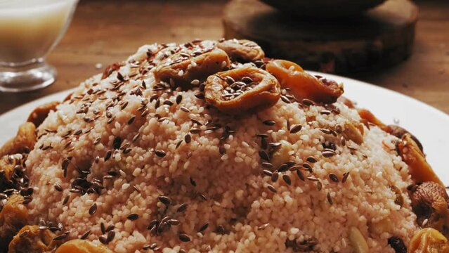 flax seed is poured into a plate with couscous with dried fruits and nuts