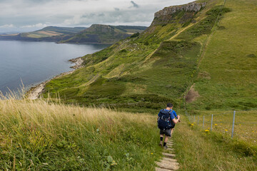 Hikers walk down a steep set of steps on the South West Coast Path in Dorset as they approach...