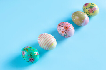 Colorful, painted for Easter, chicken eggs lie sub-diagonally on a blue background