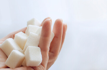 Lump sugar in hand close-up. Neutral background, copyspace.