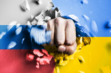 A fist punches through a concrete wall with the colors of the Ukrainian and russian flags. The...