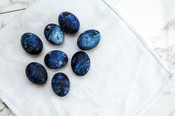 Cosmic colored eggs lie on a white waffle towel on a marble table. Easter eggs on the table