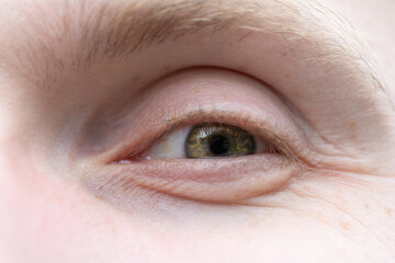 Fototapeta premium Happy green eye of a man close-up. The eye of a European blond male with freckles
