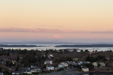 High angle view of the Oak Bay area and Washington State’s Mount Baker in soft focus background during a winter sunset from the Walbran Park Lookout, Victoria, British Columbia, Canada