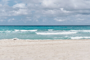 Fototapeta na wymiar Atlantic sandy beach of Cuba, resort Varadero. Waves and cloudy sky. Scenic seascape