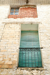 Fototapeta na wymiar Old house facade with rusty balcony and green blind