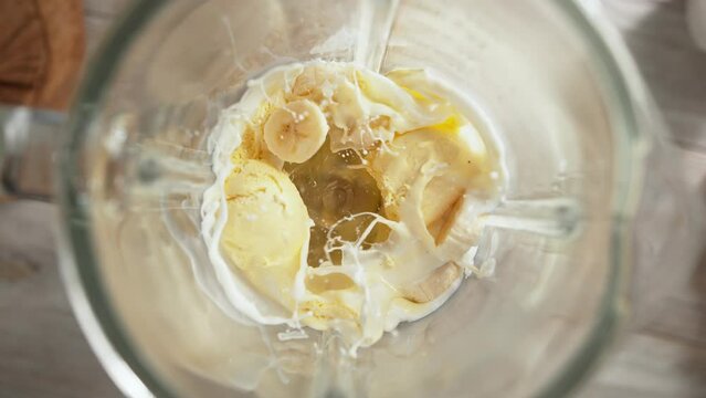 Vanilla Ice Cream and Banana Milkshake Mixed in Blender in Slow Motion - Top View, Camera Moves Out