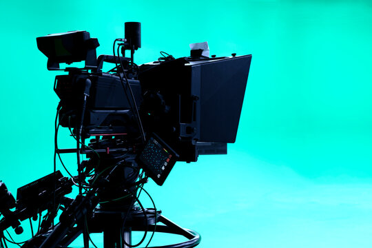 The camera on the tripod, led floodlight, prompter and a monitor on a green background. The chroma key. Green screen