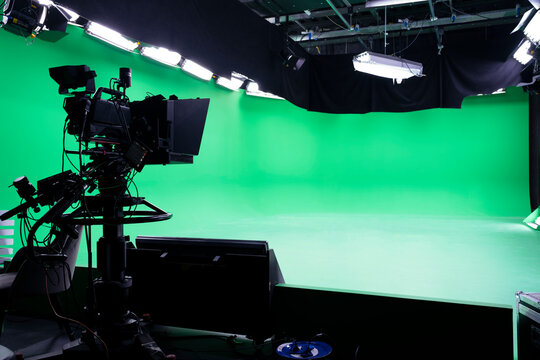 The camera on the tripod, led floodlight, spotlight, prompter and a monitor on a green background. The chroma key. Green screen. Broadcast industry
