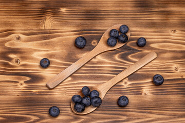 Wooden spoon with berries on wooden background.