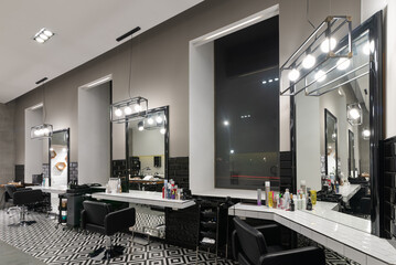Interior of the barbershop with mirrors, chairs and other equipment near windows