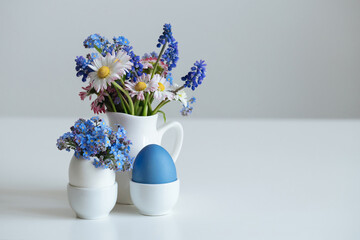 Easter eggs and bouquets of flowers on white background. Cute Easter composition. Copy space.