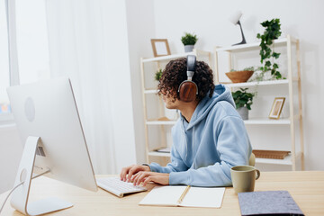 guy with curly hair in headphones sitting in front of the computer technologies