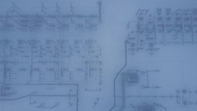 Aerial view of a high voltage electrical substation in cold snowy winter season.