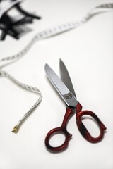 Tailor's scissors in background with meters and cut fabrics, on a white table, in a workshop. Close-up. Work.