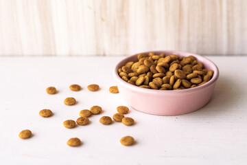 Pet dry food full pink bowl on white background. Dog cat diet concept. Close up. Text copy space.
