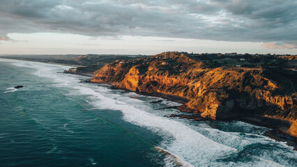 Panoramic view of Muriwai cliff side with the ocean waves at sunset