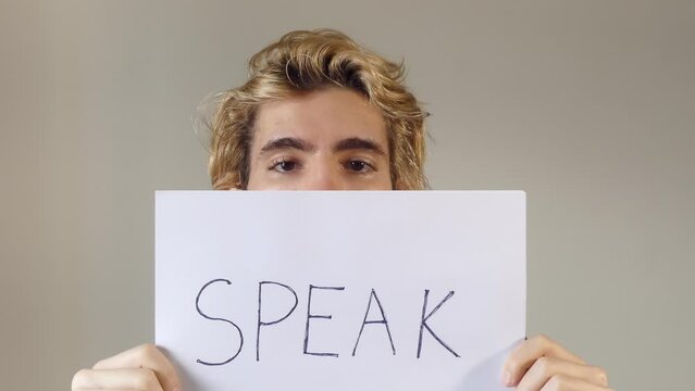 Adult Young Man Holding A Paper Message With The Text Speak, covering his face, a concept of freedom of speech, 4k resolution