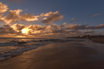 Fototapeta na wymiar puesta de sol en la playa, olas rompiendo y oleaje
