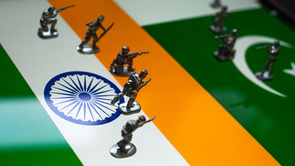 The concept of the economic and political crisis between Pakistan and India, toy soldiers attacking each other against the background of national flags.