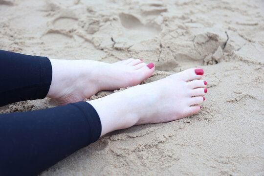 beautiful feet on the beach with painted nails