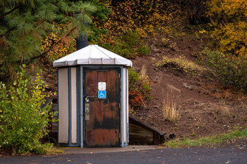 Single vault toilet located along a forested hillside