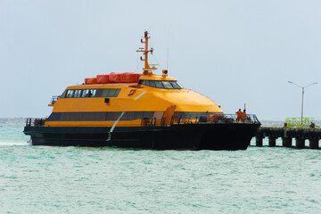The orange ferry is mooring at the pier. The ship arrived at the parking lot. Marine ship.