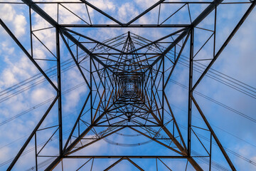 A symmetrical view looking up through the inside of an electricity pylon